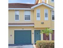 Inviting two-story home with a teal garage door, updated front door, and tropical shrubbery at 12212 Wild Iris Way # 106, Orlando, FL 32837