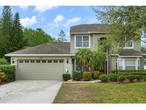 Two-story home boasts an attached garage, lush landscaping, and mature trees in a well-maintained front yard at 13609 Sky Blue Ct, Orlando, FL 32828
