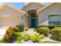 Charming single-story home featuring an arched entryway, teal front door, and manicured landscaping at 14155 Portrush Dr, Orlando, FL 32828