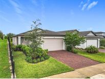 Charming single-Gathering home with a two-car garage, landscaped yard, and a beautiful red brick driveway at 2241 Mystic Maze Ln, Minneola, FL 34715