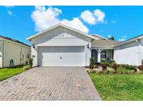 Charming home with brick-paved driveway, manicured lawn, and a white two-car garage at 2458 Cliff Way, St Cloud, FL 34771