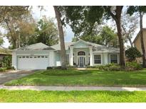 Charming one-story home with a light blue exterior, well-maintained lawn, and a two car garage at 4201 Old Trafford Way, Orlando, FL 32810