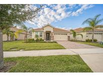 Charming single-story home featuring a well-manicured lawn, brick driveway, and a tile roof at 8907 Fallen Oak, Davenport, FL 33897