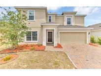 Inviting two-story home featuring a brick-paved driveway, attached two-car garage and manicured landscaping at 116 Green Branch Blvd, Groveland, FL 34736