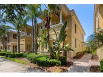 Charming yellow townhome featuring lush tropical landscaping and a welcoming entrance at 11918 Nautica Dr, Orlando, FL 32827
