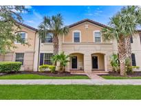 Charming two-story townhome with a well-manicured lawn and beautiful palm trees in front at 2030 Majorca Dr, Kissimmee, FL 34747