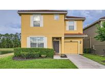 Inviting two-story home featuring a well-maintained lawn and an attached one car garage at 2999 Buccaneer Palm Rd, Kissimmee, FL 34747