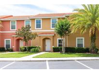 Inviting townhouse exterior featuring a terra cotta roof, well-kept lawn, and vibrant landscaping at 3069 White Orchid Rd, Kissimmee, FL 34747