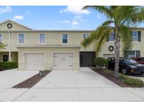 Inviting two-story townhome with attached two-car garage, well-manicured landscaping, and neutral exterior paint at 312 Arbor Lakes Dr, Davenport, FL 33896