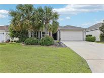 Charming single-story home featuring a two-car garage, well-maintained lawn, and mature palm trees at 3198 Abana Path, The Villages, FL 32163