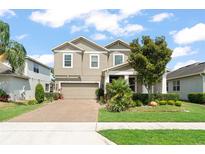 Two story home with a two car garage, brick driveway, manicured lawn and mature trees at 488 Kistler Cir, Clermont, FL 34715