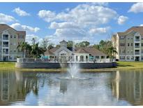 Beautiful clubhouse overlooking the lake with a fountain and palm trees against a blue sky at 5276 Cane Island Loop # 302, Kissimmee, FL 34746