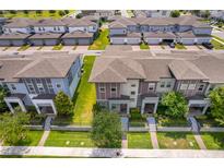 An aerial view shows multi-story townhomes with well-manicured landscaping and symmetrical architectural details at 6132 Bimini Twist Loop, Orlando, FL 32819