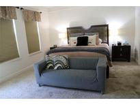 Bright bedroom featuring a gray settee, plush carpet, and a comfortable king-size bed at 9005 Reflection Pointe Dr, Windermere, FL 34786