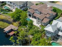 Stunning aerial view of a luxury waterfront home with a private pool and boat dock on a picturesque lake at 9916 Lone Tree Ln, Orlando, FL 32836