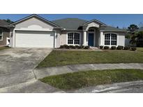 Charming single-story home featuring a manicured lawn, a blue front door, and an attached two-car garage at 1115 Fidelma Ct, Orlando, FL 32824