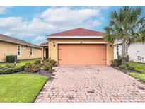 Charming single-story home featuring a brick driveway, lush landscaping, and a two-car garage at 145 Palazzo Ln, Kissimmee, FL 34759