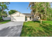 Charming single-Gathering home with an attached garage, light beige siding and well-manicured lawn and mature tree at 1550 Maxwell Ln, Deltona, FL 32738
