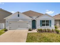 Charming single-story home featuring a two-car garage, teal door, manicured lawn and lovely landscaping at 1693 Barberry Dr, Kissimmee, FL 34744