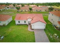 Well-maintained single-Gathering home with lush green lawn and attached garage, surrounded by similar properties at 459 Cinnamon Dr, Kissimmee, FL 34759