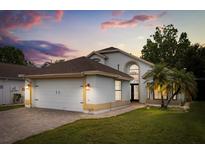 Charming single-Gathering home with a well-manicured lawn, two car garage, and tropical landscaping against a colorful sunset sky at 5672 Parkview Lake Dr, Orlando, FL 32821