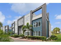 Modern townhome exterior featuring blue and gray siding, with lush landscaping and a contemporary design at 7740 Sandy Ridge Dr # 216, Reunion, FL 34747