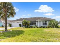 Charming single-story home featuring a lush lawn, well-maintained landscaping, and a spacious two-car garage at 7760 Indian Ridge N Trl, Kissimmee, FL 34747