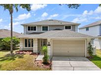 Charming two-story home featuring a well-manicured lawn and a two-car garage with palm tree at 8522 Blue Horizon Ct, Kissimmee, FL 34747
