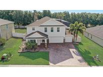 Stunning two-story home featuring a three-car garage, brick paver driveway and beautifully landscaped front yard at 10231 Lenox St, Clermont, FL 34711