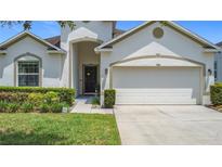 Charming single-Gathering home featuring a two-car garage, well-manicured landscaping and a walkway to the front door at 1061 Suffragatte Cir, Haines City, FL 33844