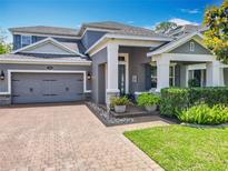 Charming two-story home with a brick driveway, beautiful landscaping, and a welcoming front porch at 1086 Calla Lily Cv, Oviedo, FL 32766