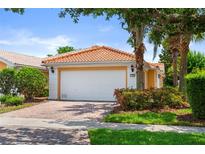 Charming single-story home featuring a red tile roof, lush landscaping, and a brick-paved driveway at 11863 Delfina Ln, Orlando, FL 32827