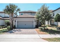 Two-story home with paver driveway, grey siding, clay tile roof, and manicured landscaping at 1340 Blue Stem Ln, Winter Park, FL 32792