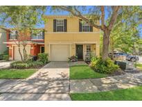 Two-story townhome with a yellow facade, attached garage, and well-maintained landscaping at 13480 Applerose Ln # 19, Orlando, FL 32824