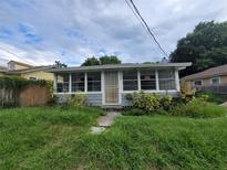 Exterior of a home featuring an enclosed porch, overgrown front lawn and weathered paint at 1620 Grand St, Orlando, FL 32805