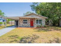 Charming single-story home with stone accents, a bright red door, and a convenient carport at 4827 Elese St, Orlando, FL 32811