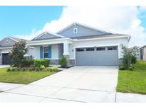 Charming single-story home with a two-car garage, manicured lawn, and stone accents at 5089 Meadow Song Dr, Okahumpka, FL 34762