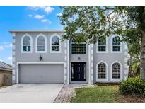 Charming two-story home showcasing arched windows, a gray facade, a well-manicured lawn, and mature trees at 520 Stonewall Ave, Haines City, FL 33844