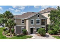 Charming multi-story condo with neutral stucco, white trim, and manicured landscaping under a blue sky at 6512 Swissco Dr # 1428, Orlando, FL 32822