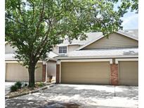 Inviting townhouse with neutral siding, attached garages, brick accents, and mature trees shading the facade at 677 Post Oak Cir # 115, Altamonte Springs, FL 32701