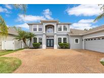 Stunning two-story home featuring a brick driveway, lush landscaping, and a welcoming double-door entrance at 8676 Currituck Sound Ln, Orlando, FL 32829
