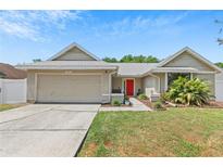 Charming single-story home with a well-maintained lawn, two-car garage, and a vibrant red front door at 10124 Pink Carnation Ct, Orlando, FL 32825