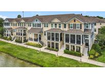 Townhomes with screened porches and green lawns along a pond offer a serene exterior with outdoor living spaces at 1027 Cedar Bay Ln, Winter Springs, FL 32708