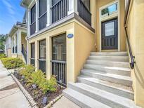 Inviting two-story townhome exterior with black railings, tan stucco, and landscaped front yard at 1027 Cedar Bay Ln, Winter Springs, FL 32708