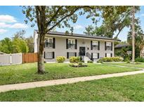 Two-story home features a well-manicured lawn, symmetrical design, and classic black shutters at 103 Cherry Hill Cir, Longwood, FL 32779