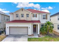 Charming two-story home featuring a red roof, two-car garage, and a beautifully landscaped front yard under a bright sky at 1744 Pine Ridge Dr, Davenport, FL 33896