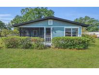Charming single story home with a screened in porch, grassy lawn, and mature landscaping at 2045 South St, Oviedo, FL 32765