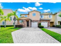 Charming townhome featuring a stone facade, two-car garage, and well-manicured landscaping at 2157 Cypress Villas Dr, Orlando, FL 32825