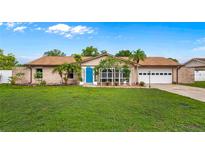 Charming single-story home with a bright blue door, lush lawn, and mature landscaping at 2316 Irlo Dr, Kissimmee, FL 34741