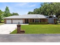 Charming single-story brick home with a well-manicured lawn, a three-car garage and mature trees at 3285 Majestic Oak Dr, St Cloud, FL 34771